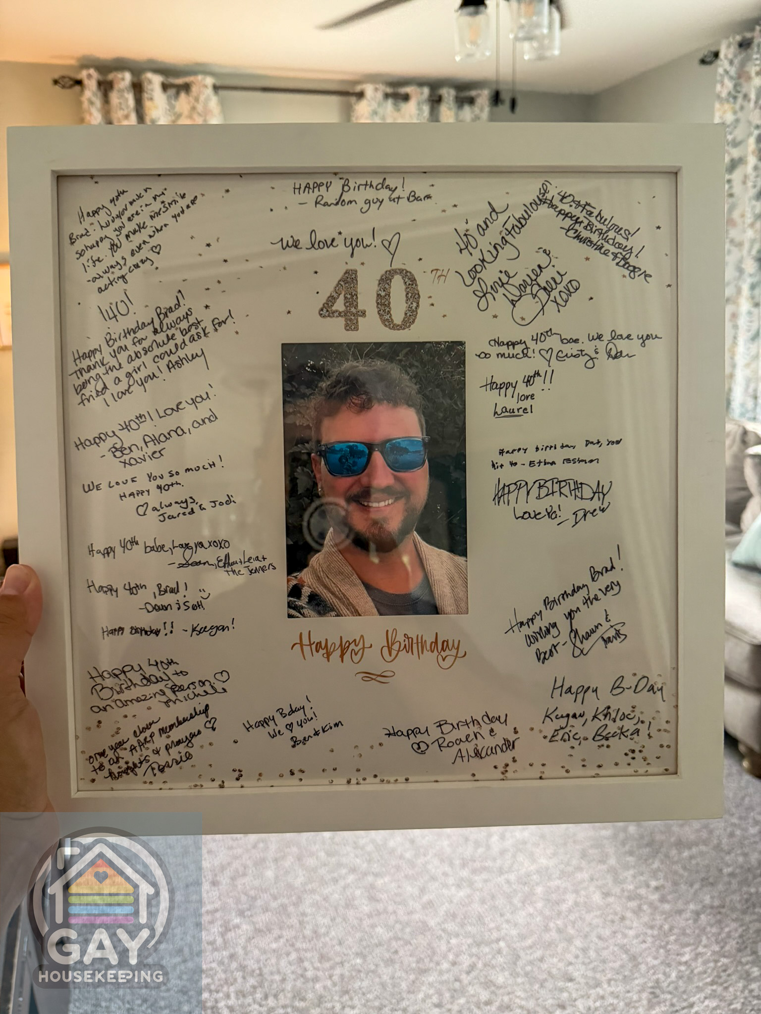 A white keepsake photo mat covered in handwritten 40th-birthday messages around a photo of Brad in blue sunglasses.
