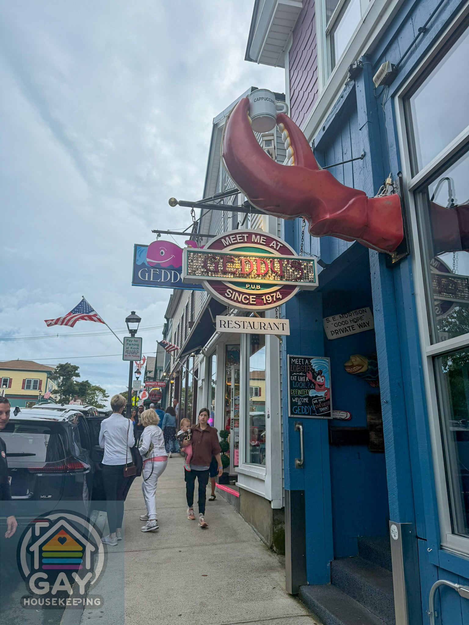 The front of Geddy's Pub in Bar Harbor, with a giant red lobster claw hoisting a cappuccino mug above the door.