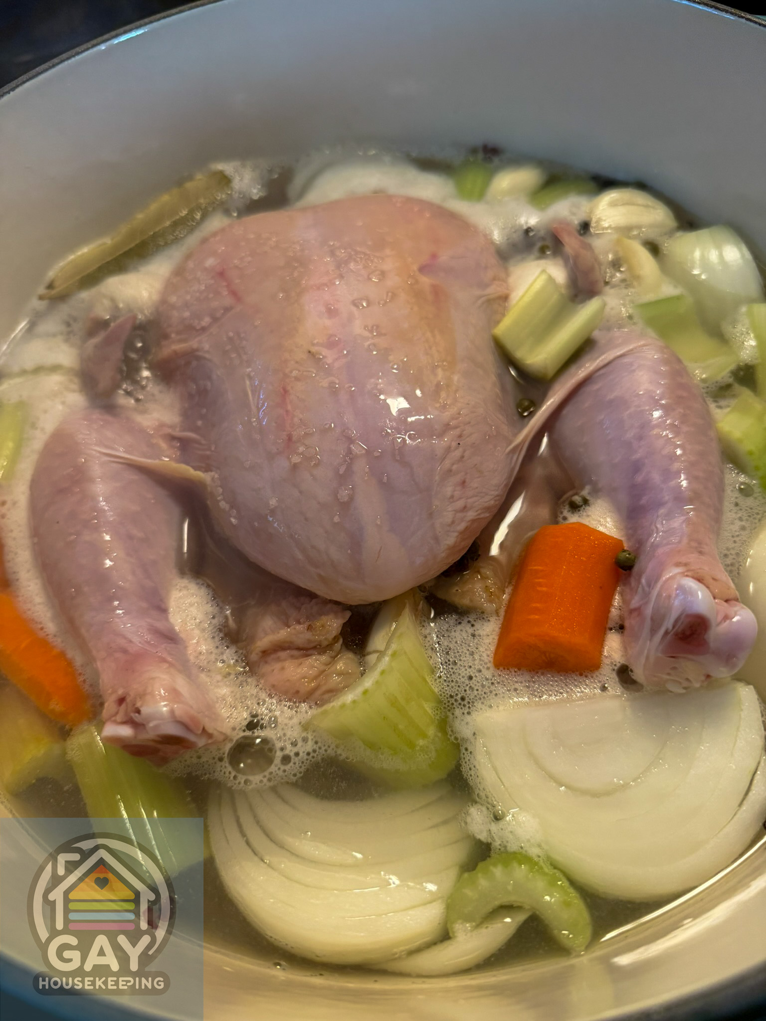 The chicken coming up to a gentle simmer, with foam beginning to gather around the vegetables.