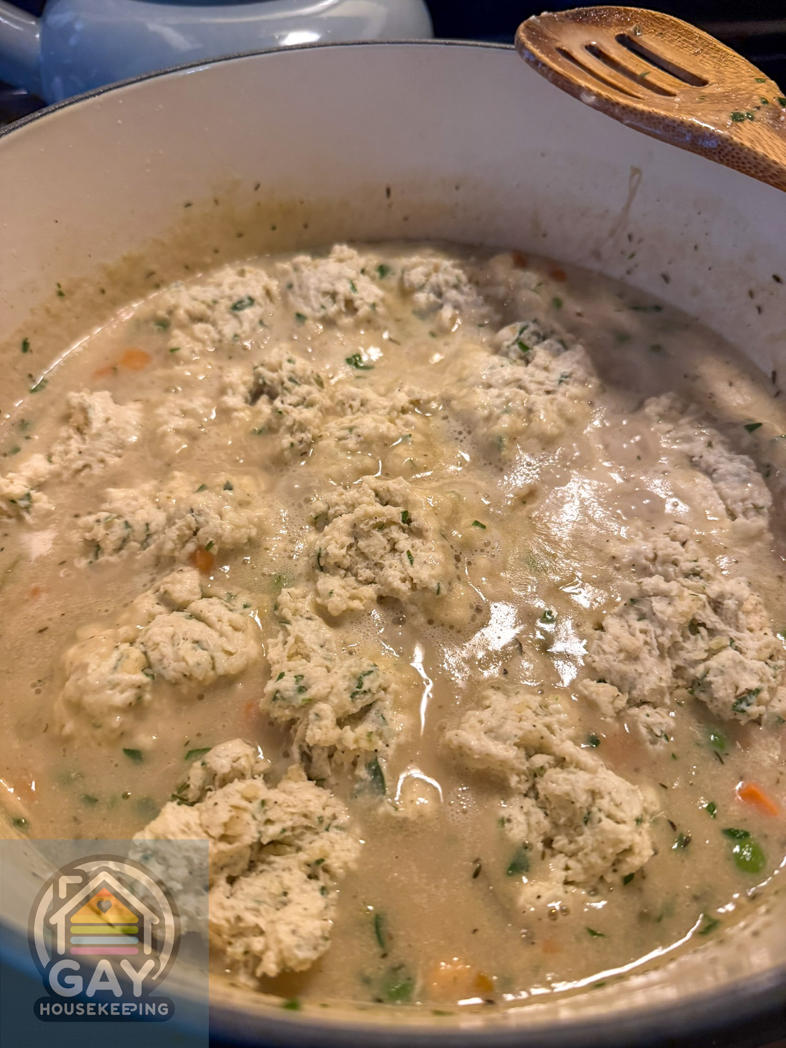 The lid comes off to reveal enormous, craggy, herb-flecked dumplings covering the top of the pot.