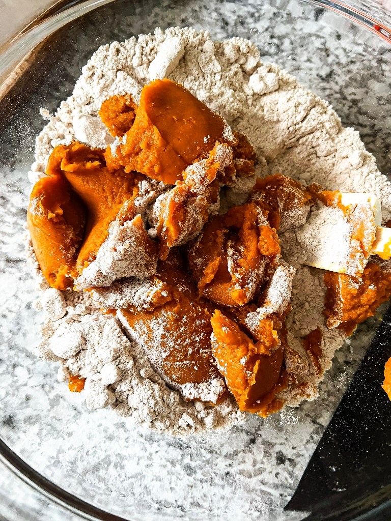 Pumpkin puree and spice cake mix combined in a glass mixing bowl, ready for baking.