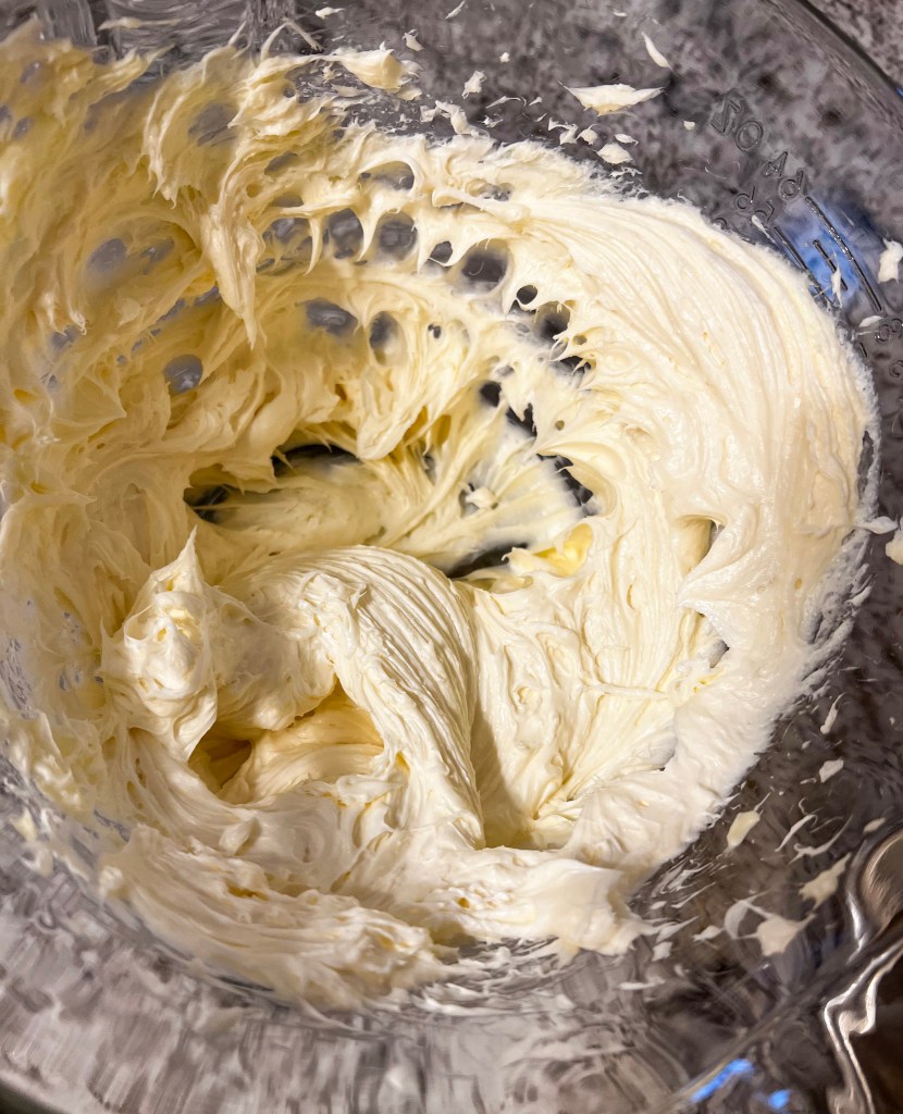 Whipped cream cheese filling in a clear mixing bowl, ready for pie layering.