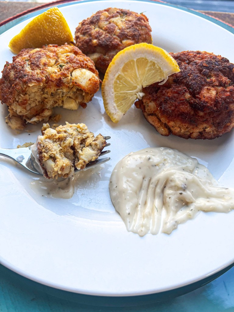 A plate of homemade cod cakes served with lemon wedges and tartar sauce.